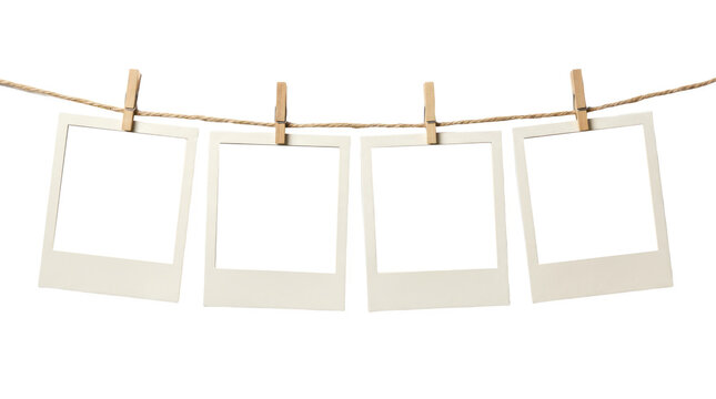 Vintage white paper photo frames hanging on a rustic twine rope with wooden clips, set of four blank polaroid style picture borders for scrapbooking albums isolated on transparent background