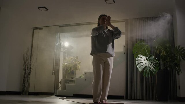 Barefoot woman flows through standing yoga balance and side stretch poses inside clean home interior