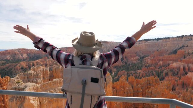 Hiker tourist with arms outstretched celebrating nature and freedom, looking at the stunning bryce canyon hoodoos in utah, usa. Backpacking and trekking american southwest adventure