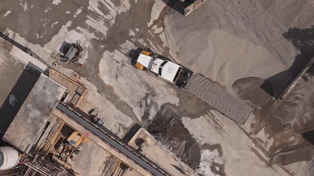Overhead aerial view of a dump truck delivering aggregate materials at a concrete mixing plant