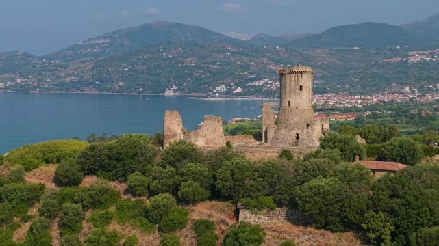 Torre di Velia ancient tower in Ascea Cilento Campania Italy 70mm telephoto drone sideways flyby over archaeological site acropolis sea and mountains background cinematic UNESCO world heritage