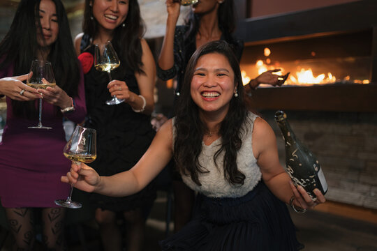 Diverse women enjoy a festive moment while toasting with champagne at a restaurant gathering with friends.