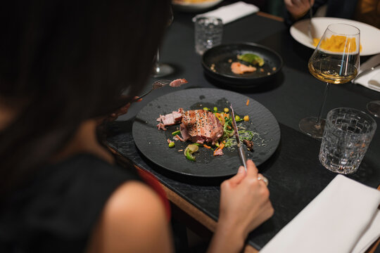 Woman enjoying her gourmet meal at a fine dining restaurant with friends.
