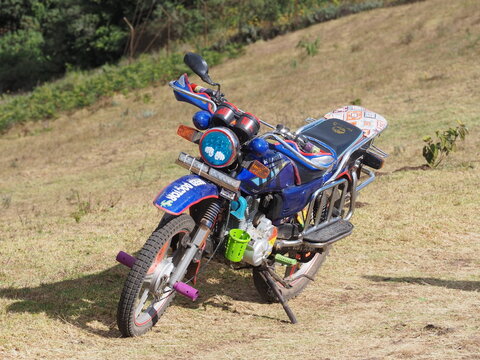 Custom Decorated Boda Boda Motorcycle Parked on Hillside Grassland