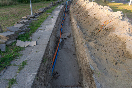 Fiber optic power cables laid inside a freshly dug ground trench outdoor