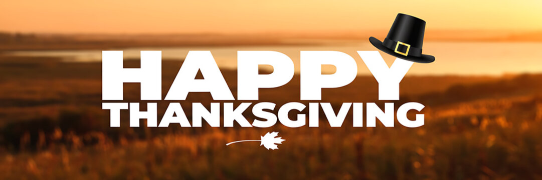Happy thanksgiving text banner with a black pilgrim hat and a small white maple leaf on a blurred autumn landscape background, at sunset