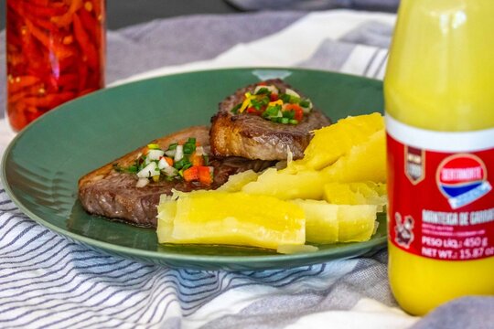 Carne de sol, a traditional northeastern Brazilian dish of salted sun-dried beef served with boiled cassava, fresh onion and bell pepper vinaigrette, chili pepper sauce and acerola juice.