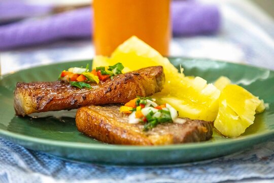 Carne de sol, a traditional northeastern Brazilian dish of salted sun-dried beef served with boiled cassava, fresh onion and bell pepper vinaigrette, chili pepper sauce and acerola juice.