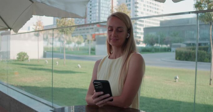 Woman Listening to Audio on Smartphone with Wireless Earbuds in Tashkent City