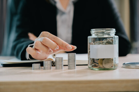 Focused professional woman manages business tax and financial planning with calm attitude while saving money in jar on her office desk
