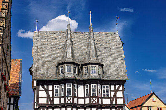 A picturesque market square with historic half-timbered houses beneath a bright blue sky; the old town with Alsfeld Town Hall