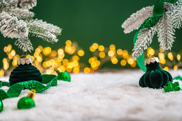 Naklejka premium A Christmas background featuring emerald baubles with gold filigree beneath a frosted pine branch, wrapped in glittering green ribbon on snow, set against deep green with twinkling lights.