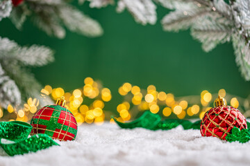 Naklejka premium A Christmas background featuring an abundant array of red and green baubles with golden patterns beneath frosted pine branches, wrapped in ribbon on snow, set against deep green with lights.
