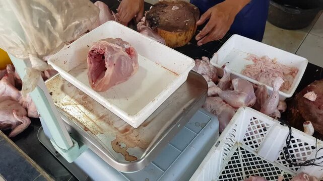 Fresh chicken meat preparation and weighing at a traditional market.
