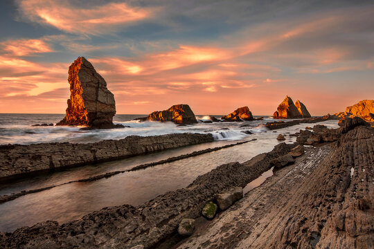 Golden sunset over the flysch formations and rocky islets of Costa Quebrada at Arnia beach in Cantabria, Spain, during low tide
