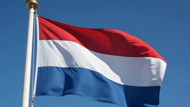 The national flag of the netherlands waving on a flagpole against a blue sky