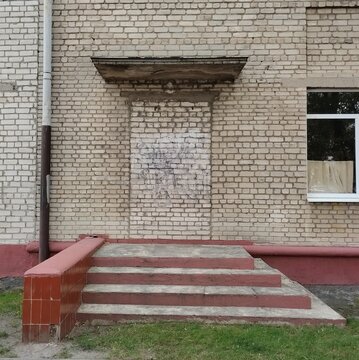 Conceptual urban view of a bricked up doorway under a concrete canopy with concrete stairs leading to a solid brick wall