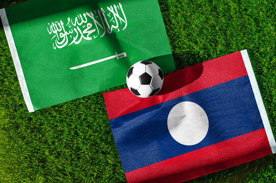Saudi Arabia vs. Laos football match. National flags on green grass with soccer ball in the middle. Football background for international match.