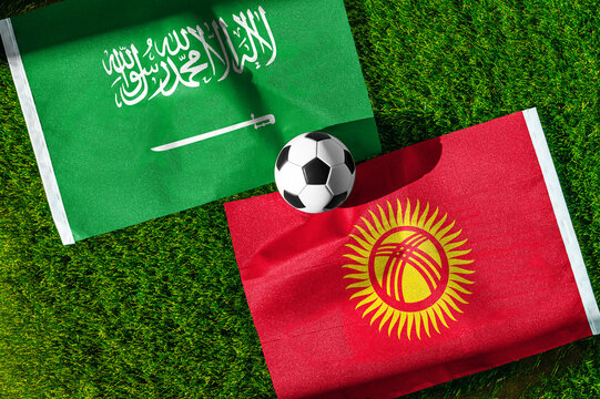 Saudi Arabia vs. Kyrgyzstan football match. National flags on green grass with soccer ball in the middle. Football background for international match.