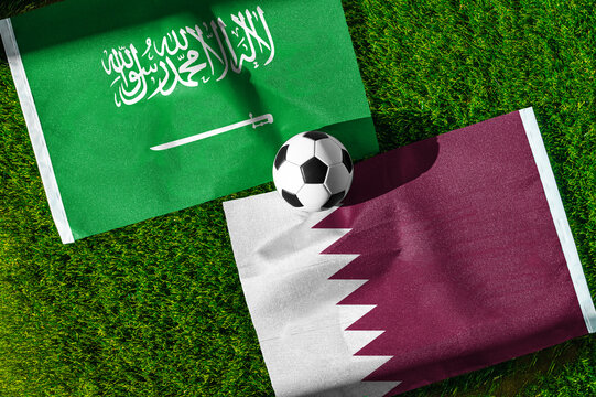 Saudi Arabia vs. Qatar football match. National flags on green grass with soccer ball in the middle. Football background for international match.