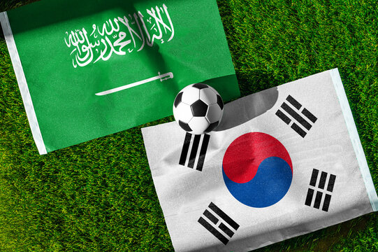 Saudi Arabia vs. South Korea football match. National flags on green grass with soccer ball in the middle. Football background for international match.