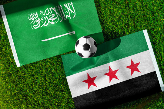 Saudi Arabia vs. Syria football match. National flags on green grass with soccer ball in the middle. Football background for international match.