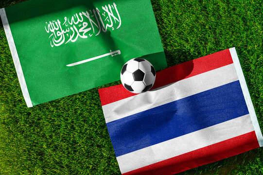 Saudi Arabia vs. Thailand football match. National flags on green grass with soccer ball in the middle. Football background for international match.