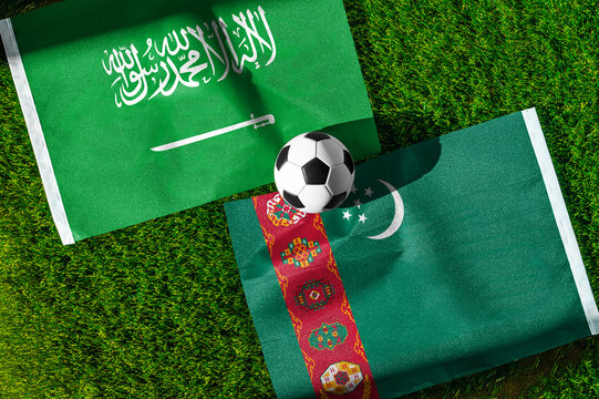 Saudi Arabia vs. Turkmenistan football match. National flags on green grass with soccer ball in the middle. Football background for international match.