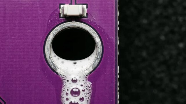 white foamy liquid filling a circular plated hole on a bright purple printed circuit board