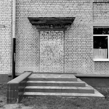 Black and white conceptual urban view of a bricked up doorway with concrete stairs.