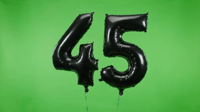 Black foil number Forty-Five balloon floating up on green screen background