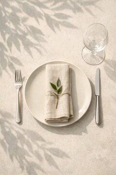 Minimal neutral table setting with linen napkin and green sprig on plate for elegant place setting and wedding menu background