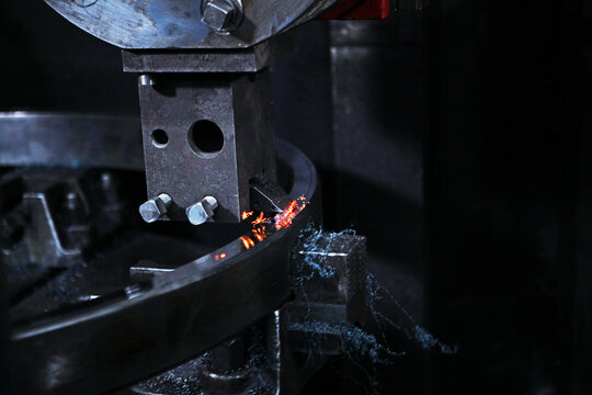 Grinding metal bearing ring on machine. Sparks and steel chips fly. Industrial manufacturing process