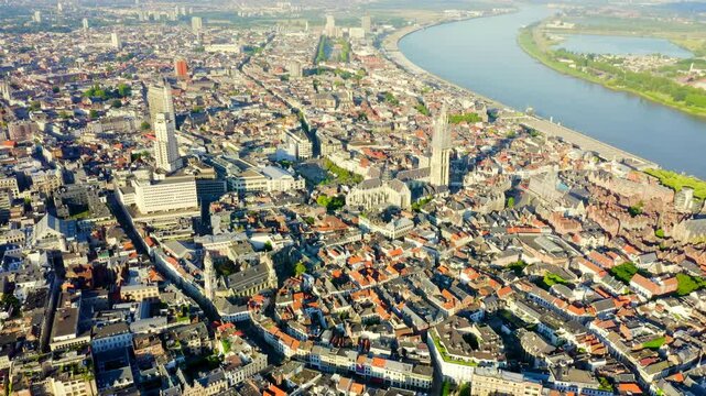Antwerp, Belgium. The Cathedral of Our Lady, its 123-meter Brabantine Gothic spire rising above terracotta rooftops, Drone footage over the Scheldt river. Drone footage