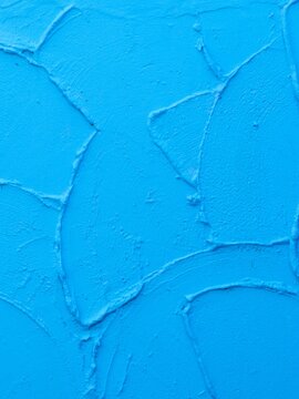 Bright blue plaster wall texture background with thick troweled stucco strokes and palette knife impasto relief for modern artistic backdrop and vibrant graphic design