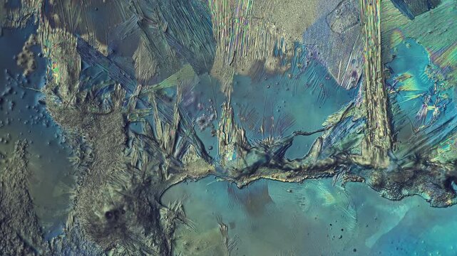 Polarized light microscopy of colorful crystal growth process under 5x microscope magnification with dark moving shadow influencing chemical crystallization of mineral texture