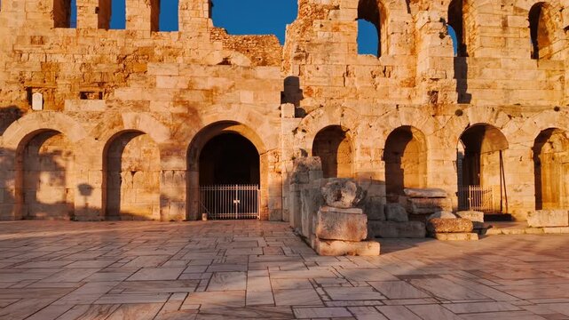 Odeon of Herodes Atticus stone arches in golden light in Athens, Greece