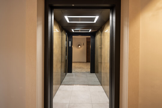 Modern hotel hallway entrance framed by elevator frame with ceiling lights