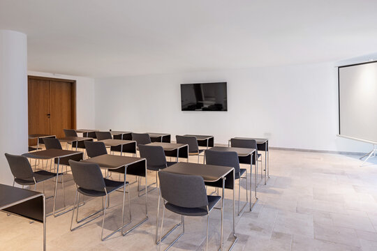 Spacious empty conference room setup with desks chairs and projector screen