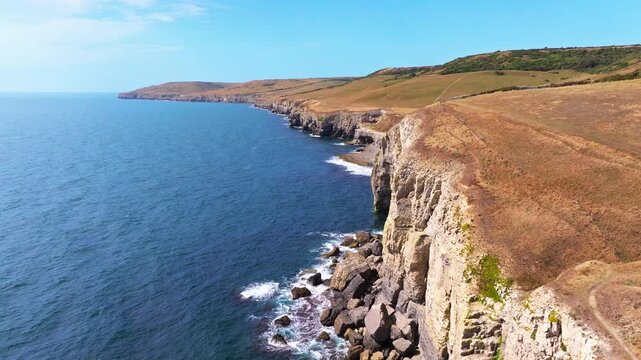 Tracking aerial shot away from the Jurassic coastline and cliffs near Dancing Ledge in Dorset UK