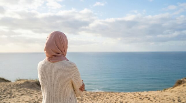 Muslim woman in hijab looking at the ocean