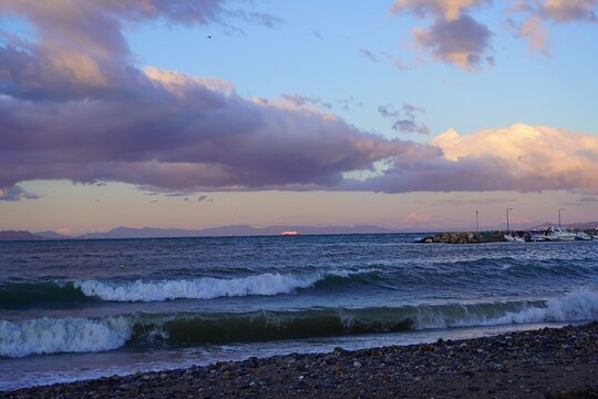 A red ship in a rough sea from the shore of Glyfada, Attica, Greece