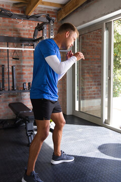 Man in layered tops and shorts practicing shadowboxing in home gym by sliding glass door