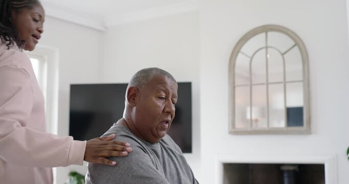 African American caregiver spotting mature man lifting hex dumbbell for rehab in living room
