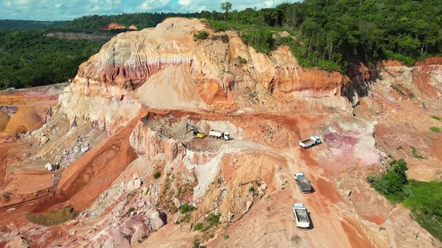 Aerial drone flyover of an open-pit aggregate mining site in the Brazilian Amazon. The footage captures the mining operation, excavation areas, heavy machinery, exposed earth, and the surrounding rain