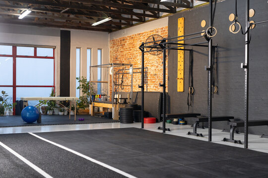 Rubber workout floor with white lane lines is anchoring warehouse gym, rig and rings are standing