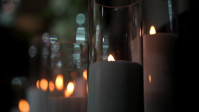Close-up of elegant white pillar candles burning with soft flames in glass holders