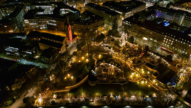 Drone aerial view of Kleine Schanze Christmas market glowing with festive lights at night in Bern, Switzerland