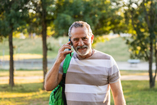 Senior man smiling talking on smartphone in park