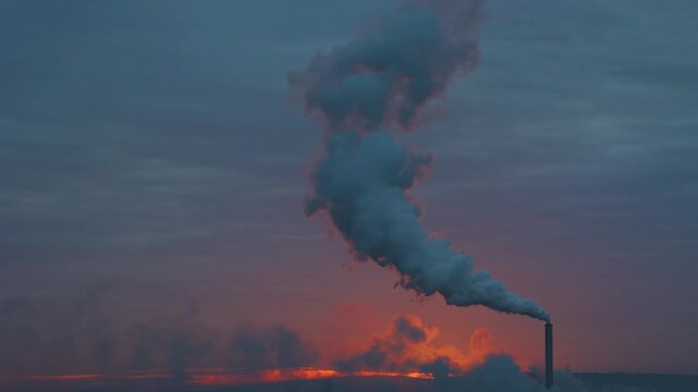 Industrial factory chimney stack releasing smoke into a twilight sky pollution industry emissions environment sunset